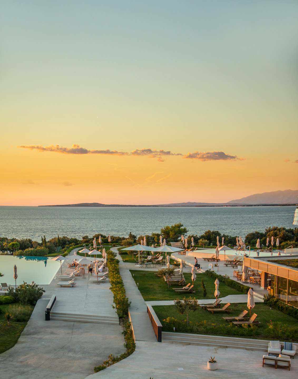 Resort di lusso sulla costa con piscina a sfioro al tramonto.