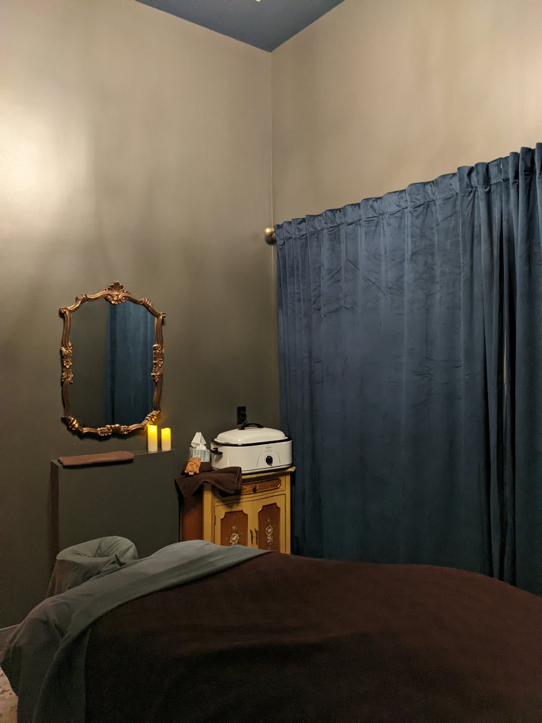 Stanza da massaggio serena con letto preparato e candele accese.