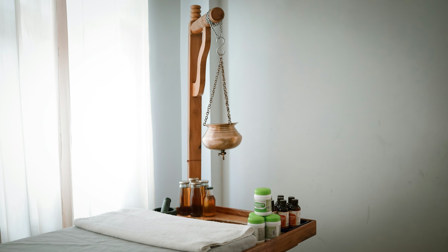 Un recipiente per Shirodhara appeso sopra un lettino da massaggio in una spa.