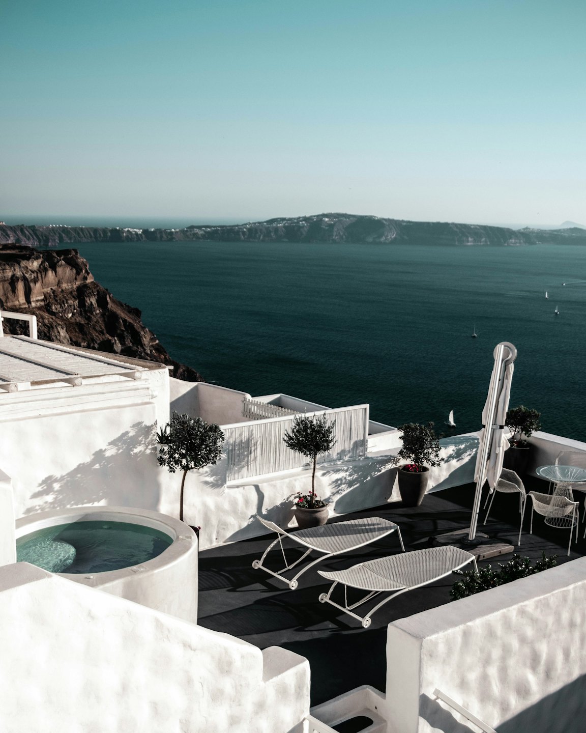 Jacuzzi e lettini prendisole su una terrazza con vista sul mare.