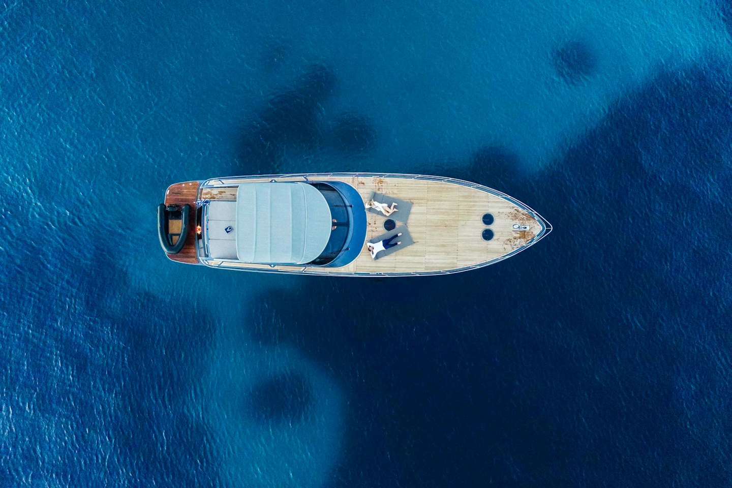 Yacht di lusso ancorato in un oceano blu con persone che prendono il sole.